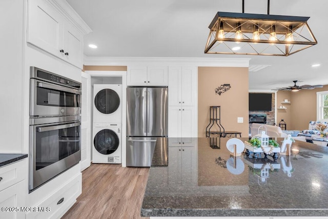 3 Andover Ct, Toms River, NJ 08757 - kitchen with stainless steel appliances, stacked washing machine and dryer, white cabinetry, ornamental molding, and dark stone countertops