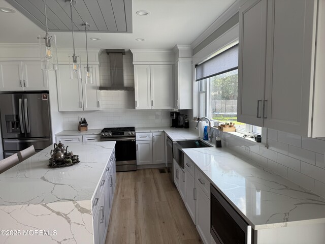 1464 Earie Way, Forked River, NJ 08731 - kitchen featuring wall chimney exhaust hood, appliances with stainless steel finishes, light wood-type flooring, hanging light fixtures, and white cabinetry