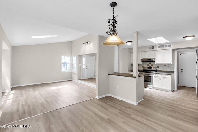 63 Oak Ln, Eatontown, NJ 07724 - kitchen featuring gas range, under cabinet range hood, a skylight, white cabinetry, and dark countertops