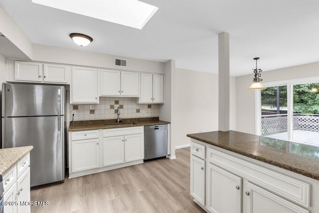 63 Oak Ln, Eatontown, NJ 07724 - kitchen with appliances with stainless steel finishes, light wood-style floors, white cabinets, tasteful backsplash, and dark stone countertops