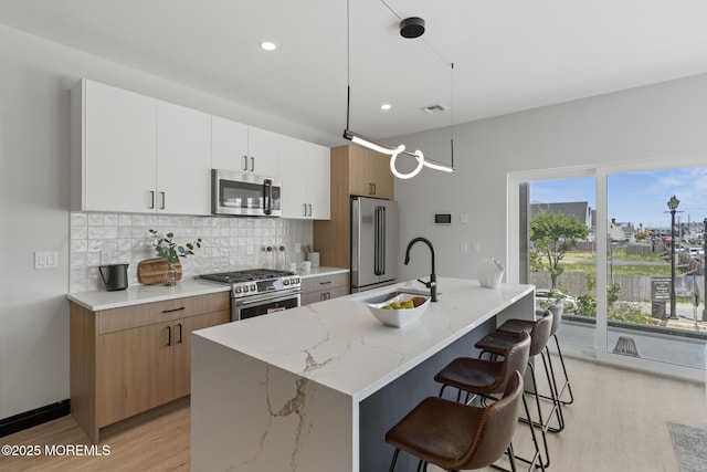 401 Boulevard 202, Seaside Heights, NJ 08751 - kitchen with stainless steel appliances, light wood-style floors, decorative backsplash, a breakfast bar, and a center island with sink
