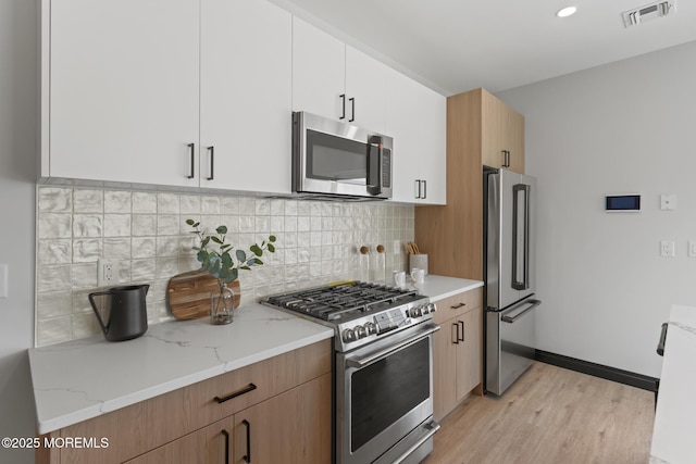 401 Boulevard 202, Seaside Heights, NJ 08751 - kitchen featuring appliances with stainless steel finishes, light stone countertops, light wood-style floors, backsplash, and white cabinets