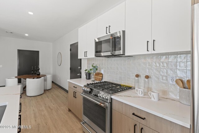 401 Boulevard 202, Seaside Heights, NJ 08751 - kitchen with appliances with stainless steel finishes, light wood finished floors, backsplash, white cabinets, and light stone countertops