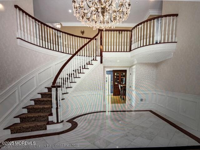 41 Marlpit Pl, Middletown, NJ 07748 - staircase with a decorative wall, inlaid floor details, a chandelier, crown molding, and a wainscoted wall