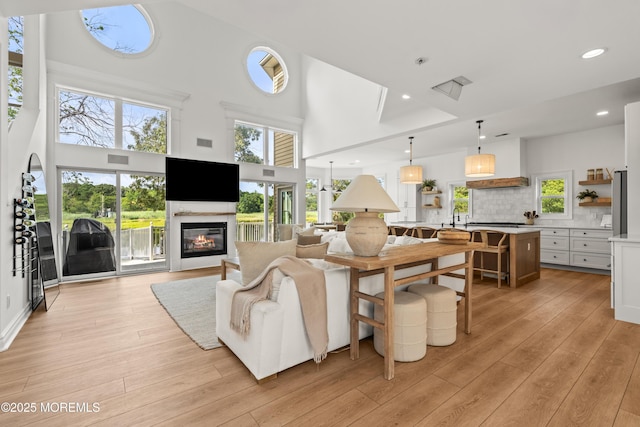 199-203 Lake Ave, Island Heights, NJ 08732 - living room featuring light wood-style flooring, a towering ceiling, a glass covered fireplace, plenty of natural light, and recessed lighting
