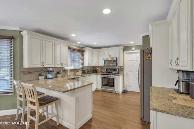 993 Sandy Cir, Manahawkin, NJ 08050 - kitchen with stainless steel appliances, a peninsula, crown molding, decorative backsplash, and light wood finished floors