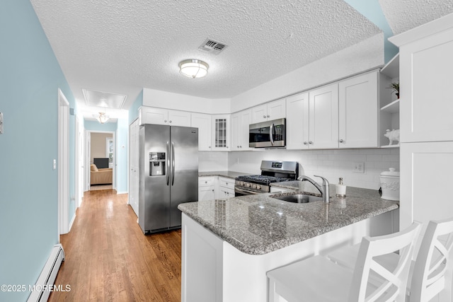 82 Spinnaker Ct, Bayville, NJ 08721 - kitchen with stainless steel appliances, a peninsula, a baseboard radiator, dark stone countertops, and glass insert cabinets