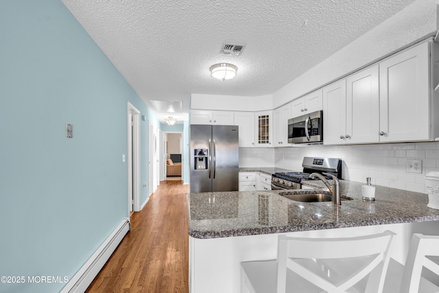 82 Spinnaker Ct, Bayville, NJ 08721 - kitchen featuring stainless steel appliances, a peninsula, glass insert cabinets, dark stone counters, and a baseboard radiator