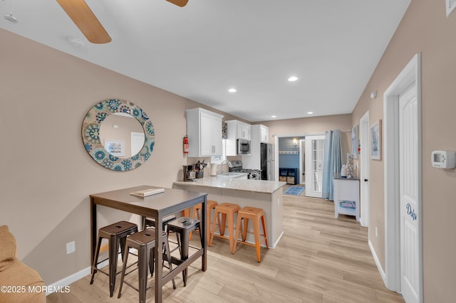241 Hiering Ave, Seaside Heights, NJ 08751 - kitchen with stainless steel appliances, a ceiling fan, a peninsula, white cabinets, and light wood finished floors