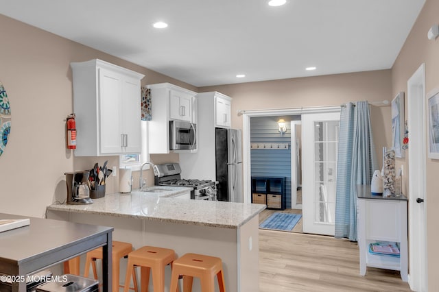 241 Hiering Ave, Seaside Heights, NJ 08751 - kitchen featuring stainless steel appliances, white cabinets, light wood finished floors, light stone countertops, and recessed lighting