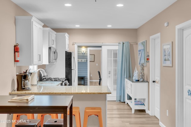 241 Hiering Ave, Seaside Heights, NJ 08751 - kitchen featuring appliances with stainless steel finishes, light stone counters, white cabinets, light wood-style floors, and recessed lighting