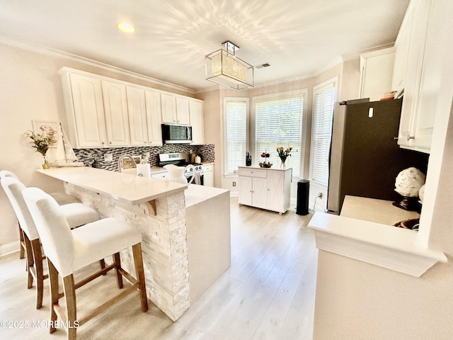205 Shinnecock Dr, Manalapan, NJ 07726 - kitchen featuring stainless steel appliances, crown molding, a peninsula, backsplash, and light wood-type flooring