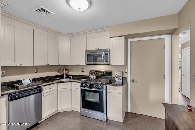 134 Marina Bay Ct, Highlands, NJ 07732 - kitchen with appliances with stainless steel finishes, light wood-style flooring, dark stone counters, and white cabinetry