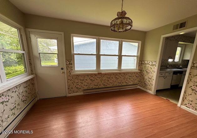 10 Arnold St, Brick, NJ 08724 - unfurnished dining area with a baseboard heating unit, light wood-type flooring, wallpapered walls, and a chandelier