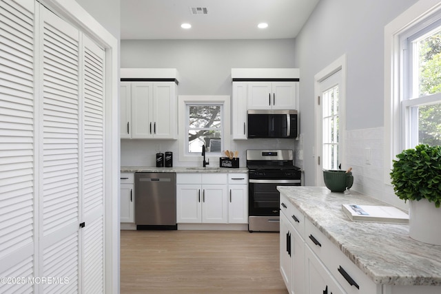 623 Central Ave, Union Beach, NJ 07735 - kitchen featuring stainless steel appliances, light stone countertops, light wood-style floors, white cabinetry, and recessed lighting