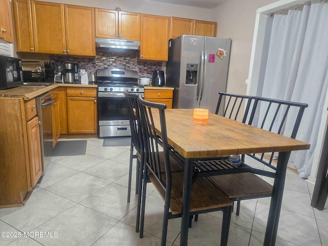 207 Delaware Ave, Cliffwood, NJ 07721 - kitchen with stainless steel appliances, under cabinet range hood, tasteful backsplash, and light tile patterned floors