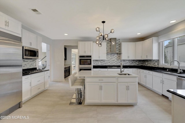 1 Country Club Dr, Deal, NJ 07723 - kitchen with appliances with stainless steel finishes, wall chimney exhaust hood, backsplash, white cabinetry, and a center island with sink