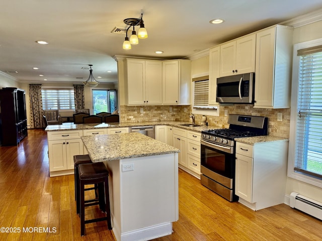 3 Tivoli St, Toms River, NJ 08757 - kitchen with stainless steel appliances, a peninsula, crown molding, a baseboard heating unit, and a center island