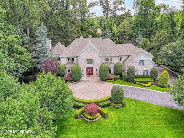 2 Red Oak, Holmdel, NJ 07733 - view of front of house featuring curved driveway, a front yard, a wooded view, and a chimney