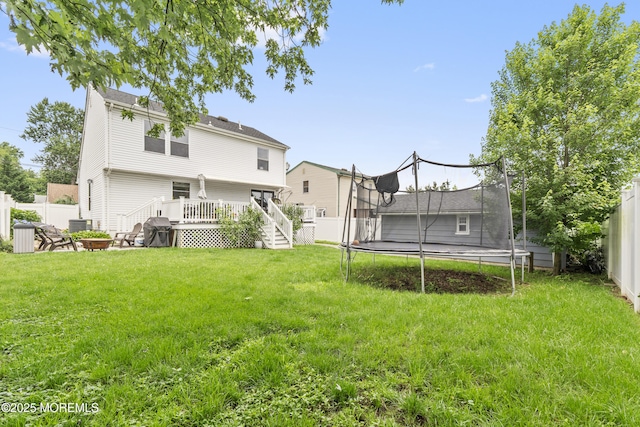 81 Lockwood Ave, Woodbridge, NJ 07095 - rear view of house featuring a trampoline, a fire pit, a wooden deck, and a fenced backyard
