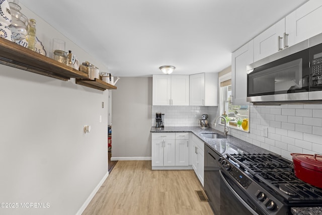 81 Lockwood Ave, Woodbridge, NJ 07095 - kitchen with stainless steel appliances, open shelves, light wood-type flooring, dark stone counters, and white cabinets