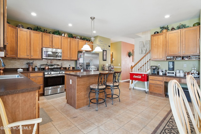 15 Savannah Dr, Barnegat, NJ 08005 - kitchen featuring appliances with stainless steel finishes, dark countertops, light tile patterned floors, a breakfast bar area, and a center island