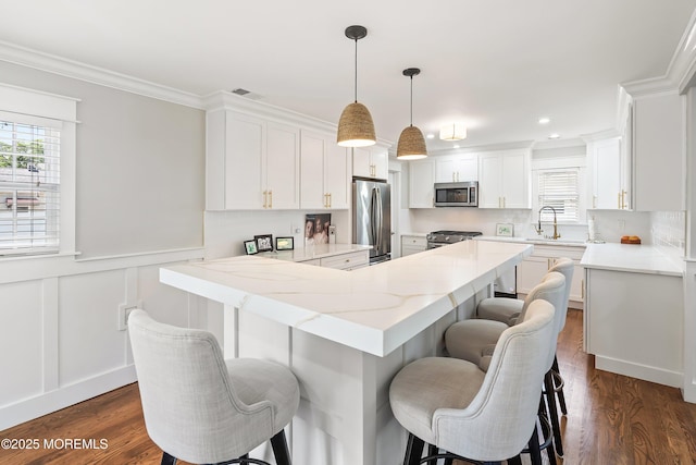 1810 Shore Blvd, Point Pleasant, NJ 08742 - kitchen with stainless steel appliances, white cabinetry, a breakfast bar area, crown molding, and dark wood finished floors