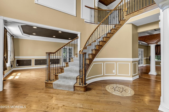 1 Ethan Dr, Farmingdale, NJ 07727 - stairway with ornate columns, crown molding, a towering ceiling, wood-type flooring, and a decorative wall
