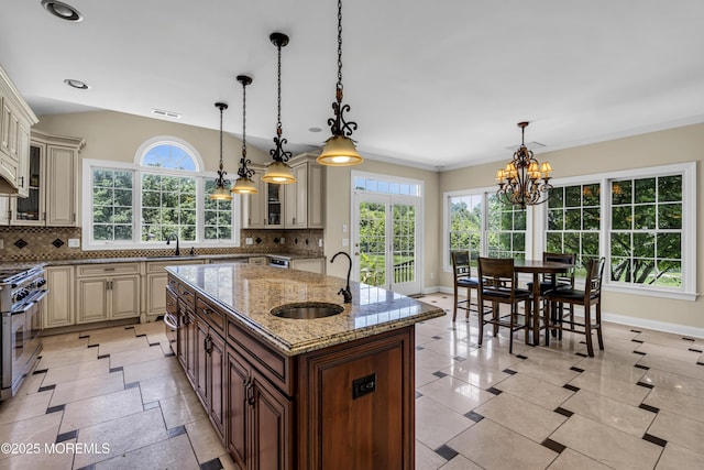 1 Ethan Dr, Farmingdale, NJ 07727 - kitchen with cream cabinets, stainless steel range with gas cooktop, a center island with sink, a chandelier, and glass insert cabinets
