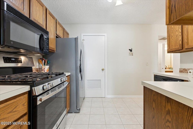 126 Sunnymede St, Englishtown, NJ 07726 - kitchen with stainless steel range with gas stovetop, black microwave, light countertops, brown cabinets, and a textured ceiling