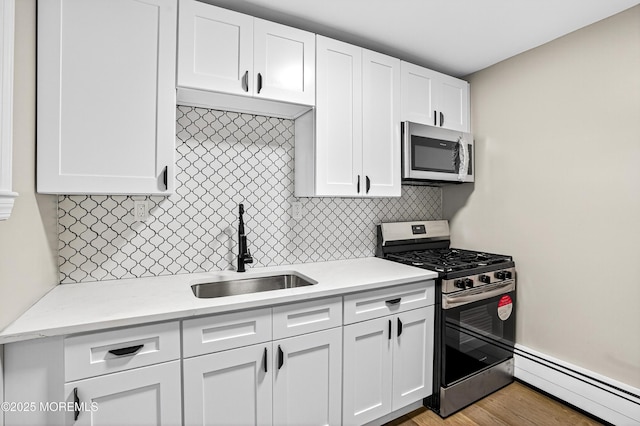 179A Buckelew Ave Unit A, Jamesburg, NJ 08831 - kitchen featuring stainless steel appliances, a baseboard heating unit, white cabinets, decorative backsplash, and wood finished floors
