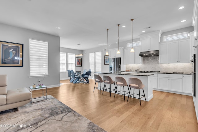 65 Ambermist Way, Forked River, NJ 08731 - kitchen with under cabinet range hood, stainless steel appliances, a kitchen breakfast bar, light wood finished floors, and open floor plan