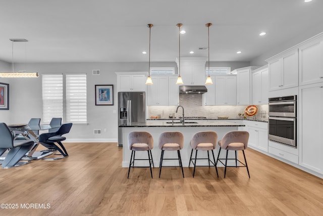 65 Ambermist Way, Forked River, NJ 08731 - kitchen with stainless steel appliances, under cabinet range hood, a kitchen breakfast bar, tasteful backsplash, and a kitchen island with sink