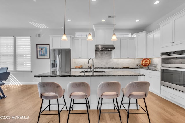 65 Ambermist Way, Forked River, NJ 08731 - kitchen with appliances with stainless steel finishes, under cabinet range hood, a kitchen breakfast bar, tasteful backsplash, and recessed lighting
