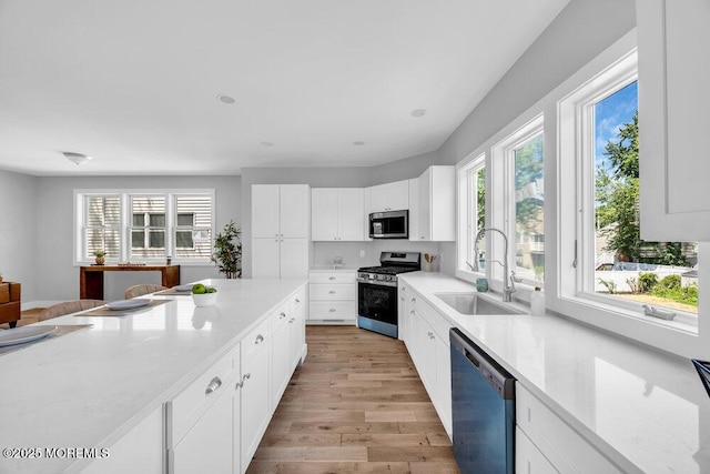 45 Shore Acres Ave, North Middletown, NJ 07748 - kitchen featuring appliances with stainless steel finishes, light wood-style floors, light stone counters, and white cabinetry