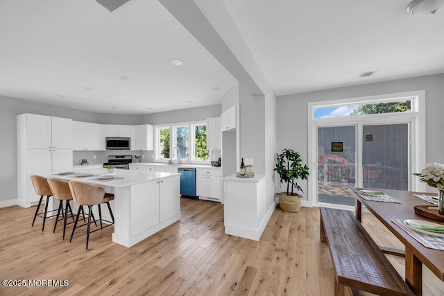 45 Shore Acres Ave, North Middletown, NJ 07748 - kitchen with stainless steel appliances, white cabinets, a center island, light countertops, and a breakfast bar area