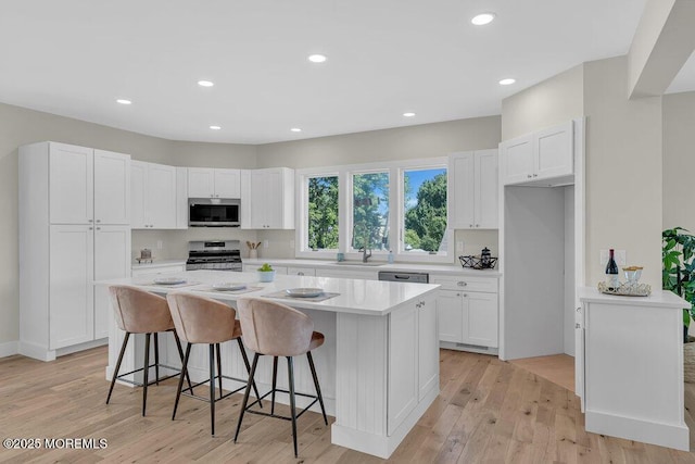 45 Shore Acres Ave, North Middletown, NJ 07748 - kitchen with appliances with stainless steel finishes, a kitchen island, white cabinetry, light countertops, and a kitchen breakfast bar