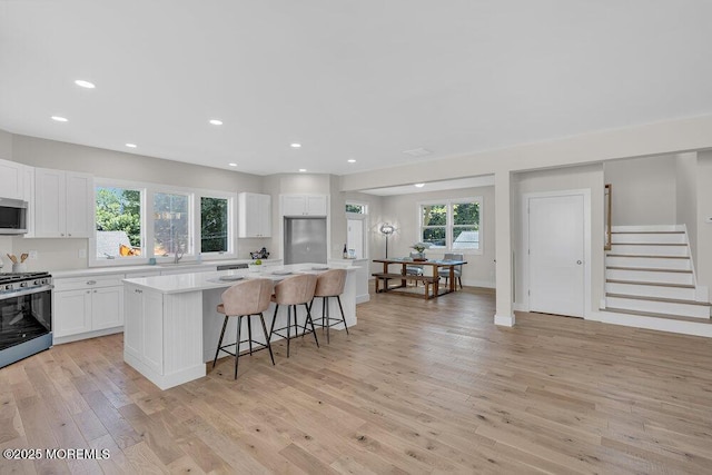 45 Shore Acres Ave, North Middletown, NJ 07748 - kitchen featuring appliances with stainless steel finishes, a kitchen island, light wood-type flooring, a kitchen breakfast bar, and white cabinetry