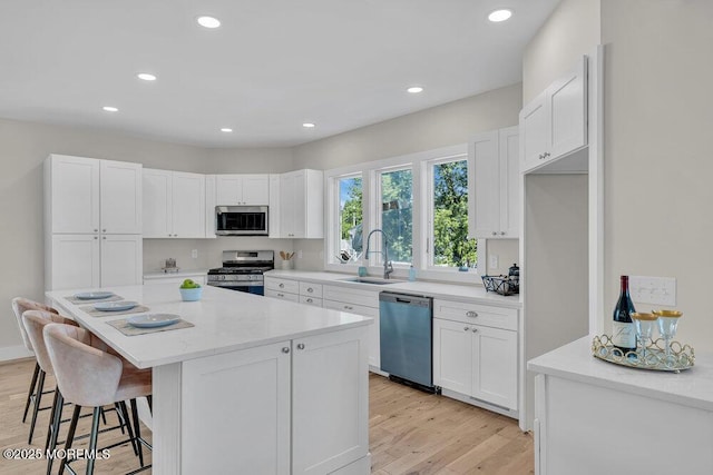 45 Shore Acres Ave, North Middletown, NJ 07748 - kitchen featuring stainless steel appliances, white cabinetry, light wood-type flooring, a center island, and a kitchen breakfast bar