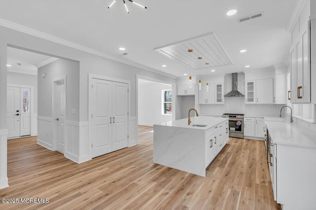 12 Outsail Ave, Barnegat, NJ 08005 - kitchen with wall chimney exhaust hood, stainless steel gas stove, light wood finished floors, white cabinets, and ornamental molding