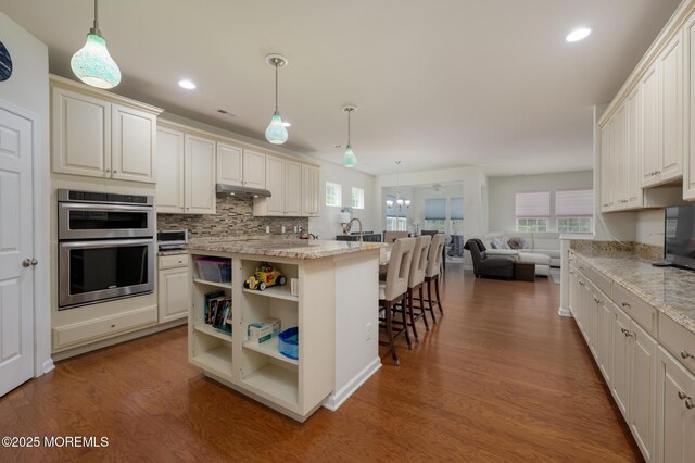 5 Gainsborough Ln, Manchester, NJ 08759 - kitchen with stainless steel double oven, wood finished floors, under cabinet range hood, open floor plan, and decorative backsplash