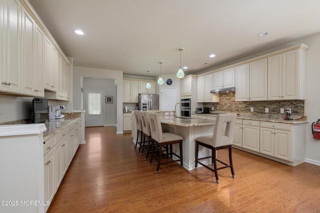 5 Gainsborough Ln, Manchester, NJ 08759 - kitchen featuring stainless steel appliances, a breakfast bar, light wood-type flooring, backsplash, and light stone counters