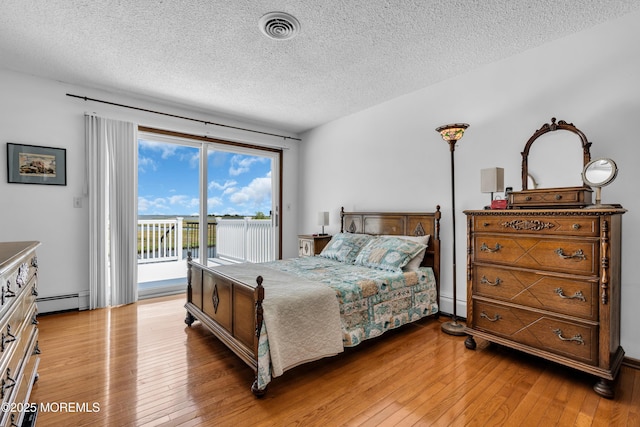 259 Cypress Dr, Bayville, NJ 08721 - bedroom with access to outside, a baseboard radiator, a textured ceiling, and light wood-type flooring