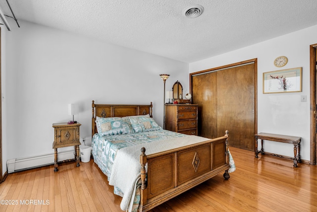 259 Cypress Dr, Bayville, NJ 08721 - bedroom with baseboard heating, light wood finished floors, a textured ceiling, and a closet