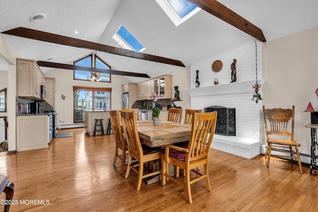 259 Cypress Dr, Bayville, NJ 08721 - dining area with a skylight, a brick fireplace, light wood-type flooring, and a baseboard heating unit