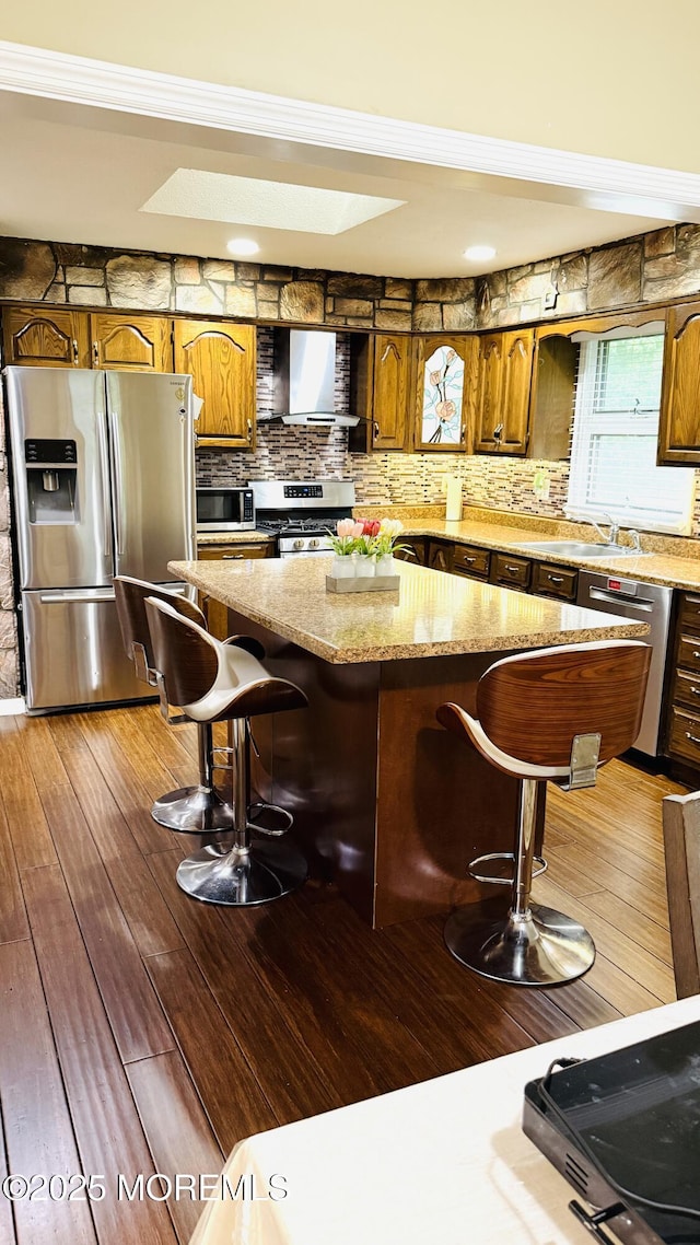 9 Longfellow Ter, Morganville, NJ 07751 - kitchen with stainless steel appliances, wall chimney exhaust hood, a skylight, a kitchen island, and a kitchen breakfast bar