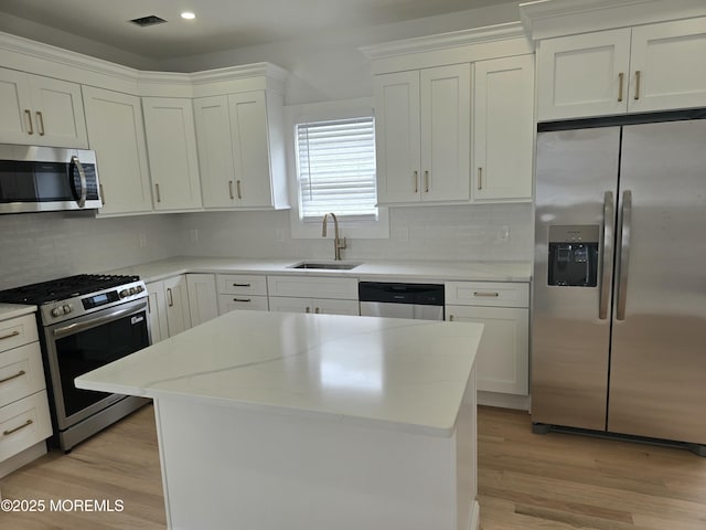 412 Ridge Ave, Neptune Township, NJ 07753 - kitchen featuring stainless steel appliances, tasteful backsplash, white cabinets, a center island, and light wood-type flooring