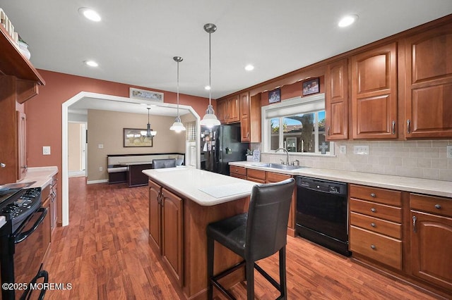14 Village Rd, Morganville, NJ 07751 - kitchen featuring black appliances, a center island, wood finished floors, backsplash, and brown cabinetry