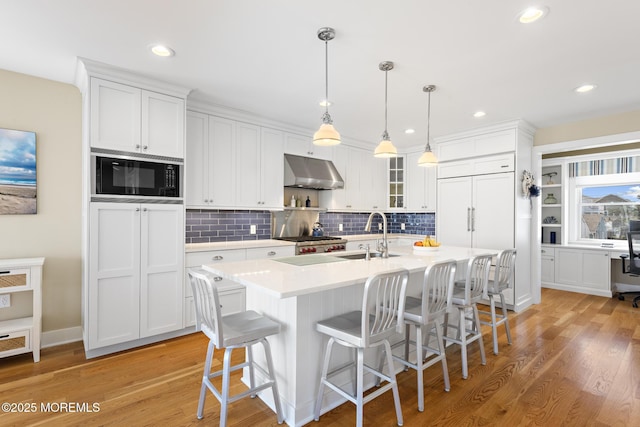 6 Pearce Ct, Manasquan, NJ 08736 - kitchen featuring black microwave, under cabinet range hood, light countertops, light wood-type flooring, and white cabinets