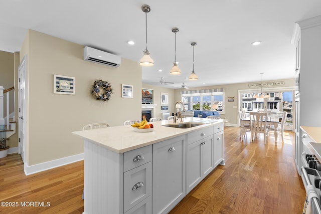 6 Pearce Ct, Manasquan, NJ 08736 - kitchen featuring ceiling fan, light wood-style flooring, a wall mounted air conditioner, a kitchen island with sink, and recessed lighting